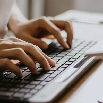 hands typing at a laptop keyboard